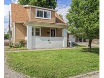 Charming two-story home with a covered front porch, landscaped lawn, and a detached garage in the back at 1720 Woodlawn Ave, Indianapolis, IN 46203