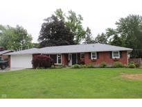 Charming brick home with attached garage, complemented by a lush green lawn and colorful landscaping at 1733 E 47Th St, Anderson, IN 46013
