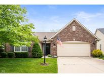 Charming brick home featuring a two-car garage, well-manicured lawn, and an American flag at 18913 Course View Rd, Noblesville, IN 46060