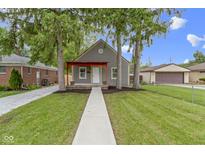 Charming home featuring a red porch and mature trees in a well-maintained yard at 2046 N Tibbs Ave, Indianapolis, IN 46222