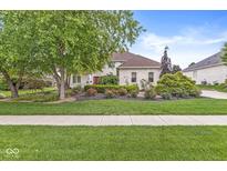 Charming brick home with a well-manicured lawn, mature trees, and vibrant flower beds showcasing curb appeal at 3655 Copperleaf Blvd, Greenwood, IN 46143