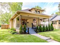 Charming bungalow with a welcoming front porch, lush greenery, and beautiful landscaping at 517 Bernard Ave, Indianapolis, IN 46208