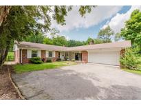 Charming single story brick home featuring a two-car garage and mature landscaping at 6030 Riverview Dr, Indianapolis, IN 46208