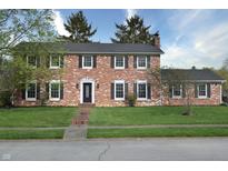 Traditional brick home featuring black shutters, manicured lawn, and mature trees at 10245 Briar Creek Ln, Carmel, IN 46033