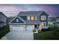 Stunning two-story home with a well-manicured lawn and a two-car garage at dusk at 16598 Dominion Dr, Fortville, IN 46040