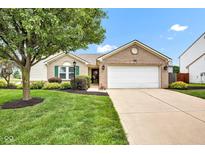Charming brick home featuring a two-car garage, manicured lawn, and colorful landscaping at 2163 Bradford Trace Blvd, Indianapolis, IN 46229