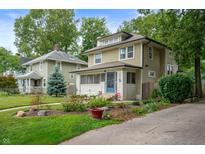 Charming two-story home with a well-maintained lawn, mature trees, and colorful flowerbeds at 4040 Carrollton Ave, Indianapolis, IN 46205