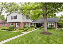 Charming two-story home featuring a mix of brick and siding, complemented by mature trees and manicured landscaping at 6115 E 65Th Pl, Indianapolis, IN 46220
