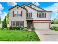 Charming two-story home featuring a brick facade, vinyl siding, and a well-manicured lawn with mature landscaping at 9001 Harrison Run Ct, Indianapolis, IN 46256
