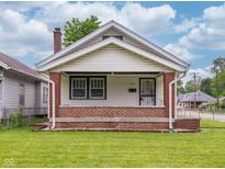 Charming single-story home with a welcoming porch, brick accents and freshly mowed lawn at 1065 36Th St, Indianapolis, IN 46208