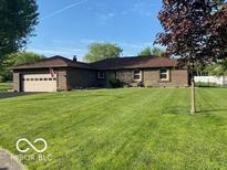 Charming brick ranch home with well-maintained lawn, attached two car garage and mature trees under a bright blue sky at 1425 Winding Trail Cir, Greenwood, IN 46142
