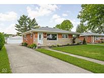 Charming single-story home with brick and stone facade, lovely landscaping, and a long concrete driveway at 2110 Allison Ave, Speedway, IN 46224