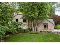 Charming two-story home with brick facade and a well-manicured front lawn nestled among mature trees at 5412 Green Hills Dr, Brownsburg, IN 46112
