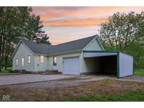 Charming home featuring a garage and large carport, all set against a backdrop of a colorful sunset at 6012 S 625 W, Pendleton, IN 46064