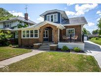 Charming two-story home with brick exterior, an arched entrance, and a cozy front porch at 949 E Southern Ave, Indianapolis, IN 46203