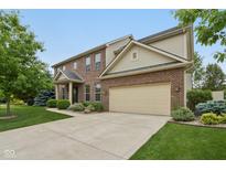 Two-story brick home featuring an attached two-car garage and manicured lawn and landscape at 11844 Pine Meadow Cir, Fishers, IN 46037
