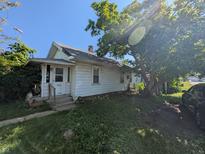 Charming single-story home featuring mature trees and a cozy front porch at 1433 N Denny St, Indianapolis, IN 46201