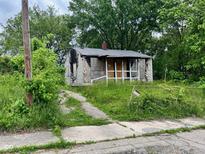 Exterior view of distressed home with overgrown yard and boarded up windows at 1516 W 20Th W St, Anderson, IN 46016