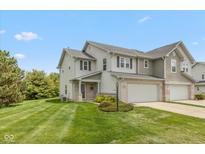 Inviting two-story townhouse featuring a lush lawn, attached garage, and neutral siding at 163 Clear Branch Dr, Brownsburg, IN 46112