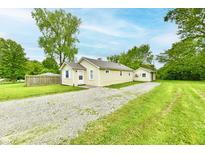 Charming single-story home with a gravel driveway and a detached garage, surrounded by lush greenery and mature trees at 1730 N Graham Ave, Indianapolis, IN 46218