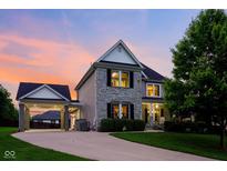 Charming two-story home with stone accents, a covered porch, and a well-manicured lawn at sunset at 2898 Violet W Ct, Columbus, IN 47201