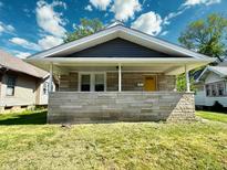 Charming single-story home featuring stone accents, covered porch, and a bright yellow front door at 4814 E New York St, Indianapolis, IN 46201