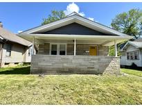 Charming home featuring a stone front porch, yellow front door, and inviting curb appeal at 4814 E New York St, Indianapolis, IN 46201