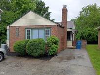 Charming brick home featuring green trim, a brick chimney, and mature landscaping at 1008 E 61St St, Indianapolis, IN 46220