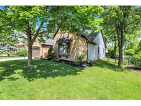 Charming brick home featuring manicured lawn and mature shade trees in a serene, suburban setting at 10560 Lighthouse Way, Indianapolis, IN 46256
