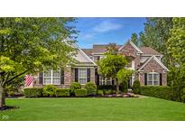 Charming brick home featuring manicured lawn, beautiful landscaping, and a welcoming facade at 11552 Buckskin Dr, Zionsville, IN 46077