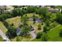 An aerial view shows a charming home with a pond, a small pier, and lush greenery surrounding the property at 6336 N Carroll Rd, Indianapolis, IN 46235