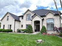 Stunning white brick home featuring a manicured lawn and beautifully landscaped front yard with mature trees and garden beds at 7823 Ashtree Dr, Indianapolis, IN 46259