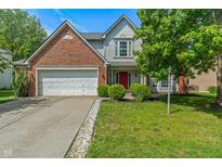 Charming two-story home features a well-manicured lawn, red door and attached two-car garage at 8376 Glen Highlands Dr, Indianapolis, IN 46236