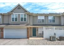 Inviting townhome features a one-car garage, green door, and charming white picket fence, creating a welcoming curb appeal at 2306 Brightwell Pl, Indianapolis, IN 46260