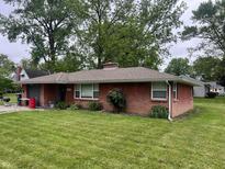 Charming brick ranch-style home with mature trees and a well-maintained front lawn at 2330 Ridgewood Dr, Anderson, IN 46012