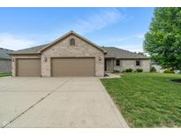 Charming brick home with a three-car garage and a well-manicured lawn on a sunny day at 2422 Oak Dr, Clayton, IN 46118