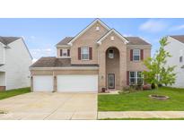 Inviting two-story brick home features a three-car garage and manicured lawn at 2502 Creekland Dr, Columbus, IN 47201