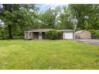 Charming single story home featuring green grass and a detached garage at 5422 Orange St, Indianapolis, IN 46203