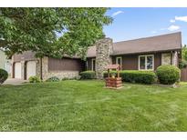 Charming home featuring a stone chimney, well-manicured lawn, and attractive landscaping at 7426 N Carroll Rd, Indianapolis, IN 46236