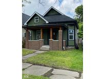 Charming bungalow with an inviting covered porch, brick supports, and green siding at 830 Villa Ave, Indianapolis, IN 46203