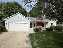 Charming home featuring a lush front lawn, attached garage, and brick chimney at 912 Delray Dr, Indianapolis, IN 46241