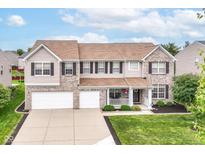 Charming two-story home featuring a manicured lawn, brick accents, and a two-car garage at 12994 Dekoven Dr, Fishers, IN 46037