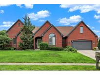 Charming brick home with lush lawn, mature trees and a two-car garage, set under a blue sky at 14492 Allison Dr, Carmel, IN 46033
