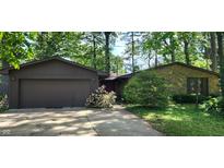 Charming home featuring a stone facade and a two-car garage surrounded by mature trees and lush landscaping at 1619 Crest Ct, Indianapolis, IN 46214