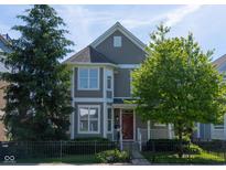 Charming two-story home with a red door, black fence, and mature trees in a well-maintained yard at 2445 N Delaware St, Indianapolis, IN 46205