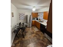 Cozy kitchen featuring stainless steel appliances, wooden cabinets, and a round glass dining table at 4113 W 30Th St, Indianapolis, IN 46222