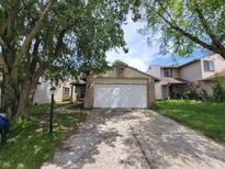 Traditional home featuring an attached garage, established trees and a concrete driveway at 5239 Traditions Rd, Indianapolis, IN 46235