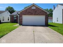 Brick home featuring an attached two-car garage and a long concrete driveway, great for parking at 5903 Brookville Lake Dr, Indianapolis, IN 46254