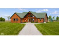 A charming log home featuring a well-maintained lawn and a quaint gravel driveway at 8981 N 325 E, Columbus, IN 47203