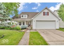 Charming two-story home with a two-car garage and inviting front porch, framed by lush greenery and a well-manicured lawn at 10717 Morristown Ct, Carmel, IN 46032
